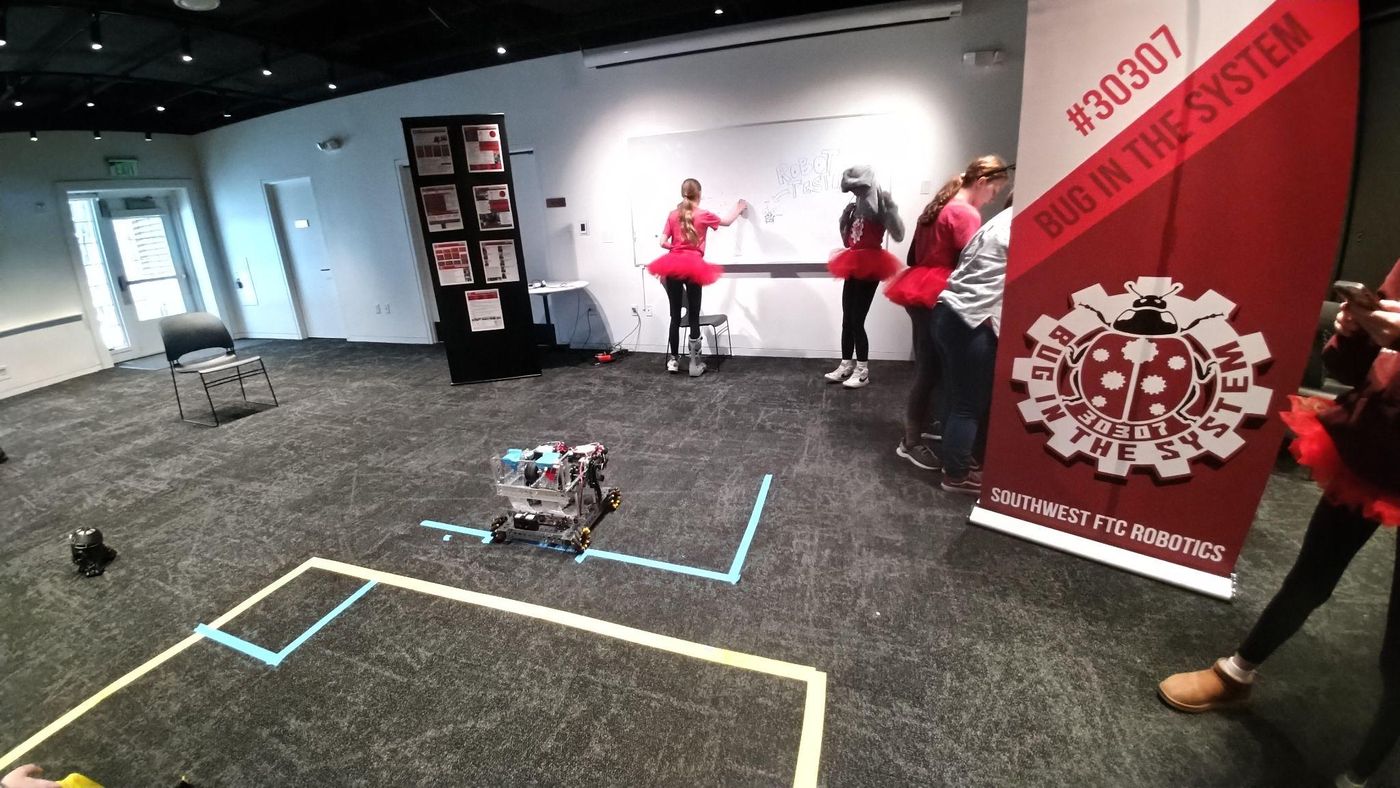 Our team and robot at a competition, next to our Bug In The System 30307 banner